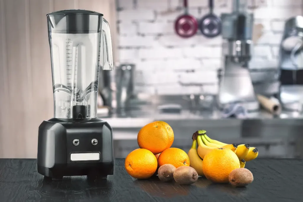 Liquidificador sobre bancada de cozinha ao lado de frutas como laranjas, bananas e kiwis